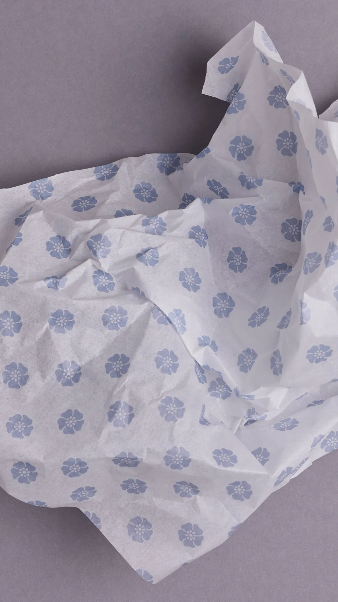 Seidenpapier mit Wadi Bildmarke (Blume) locker gefaltet auf grauem Hintergrund