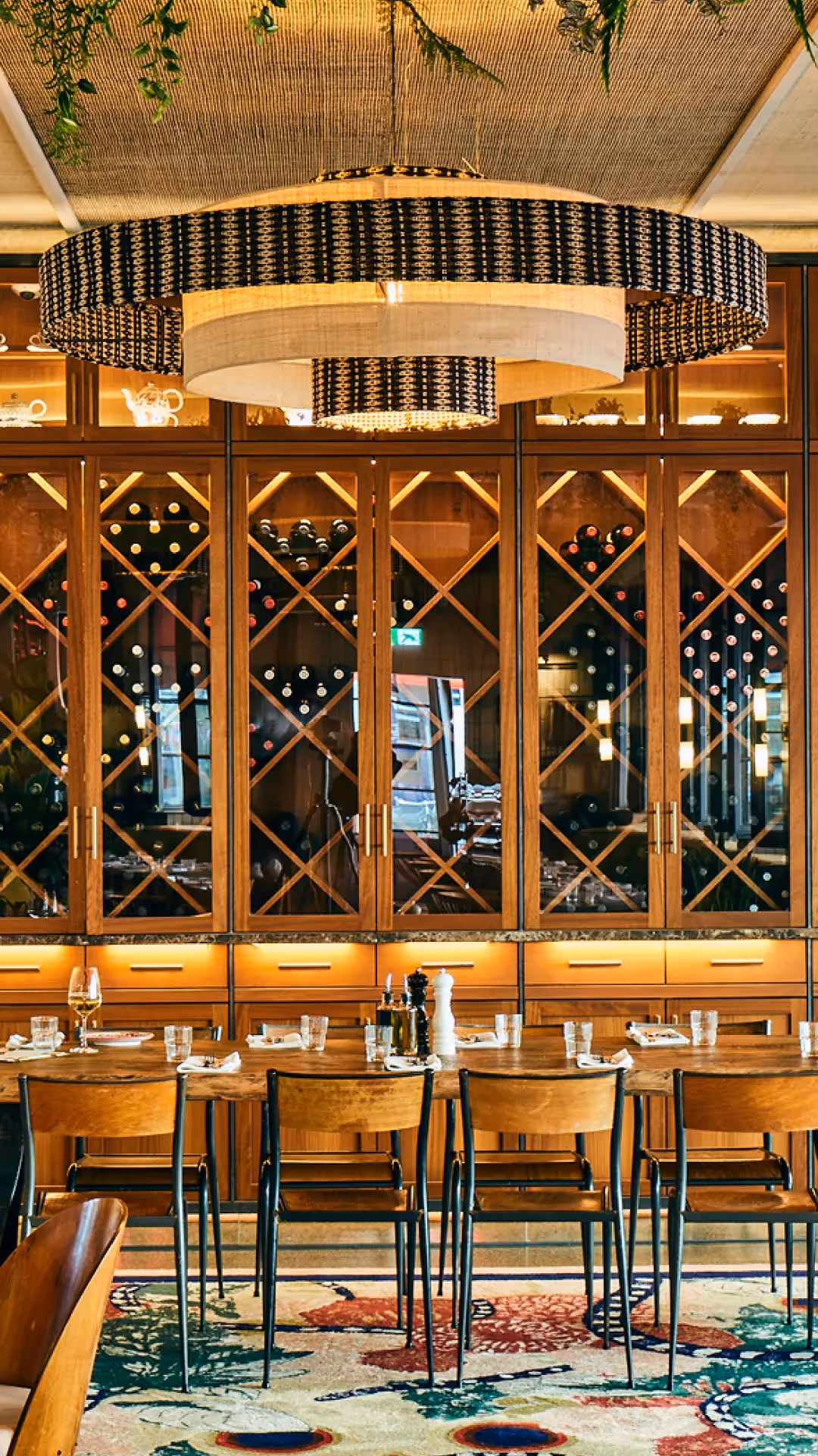 Restaurant-Innenraum mit großer Weinwand, Holzregalen und gedeckten Tischen