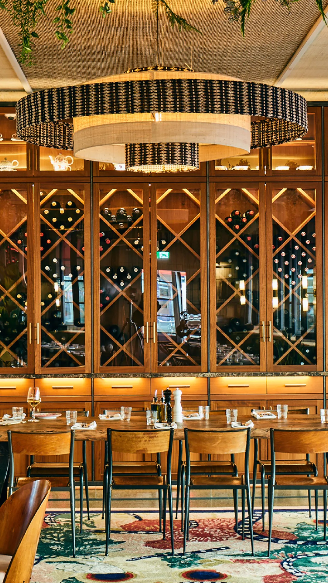 Restaurant-Innenraum mit großer Weinwand, Holzregalen und gedeckten Tischen