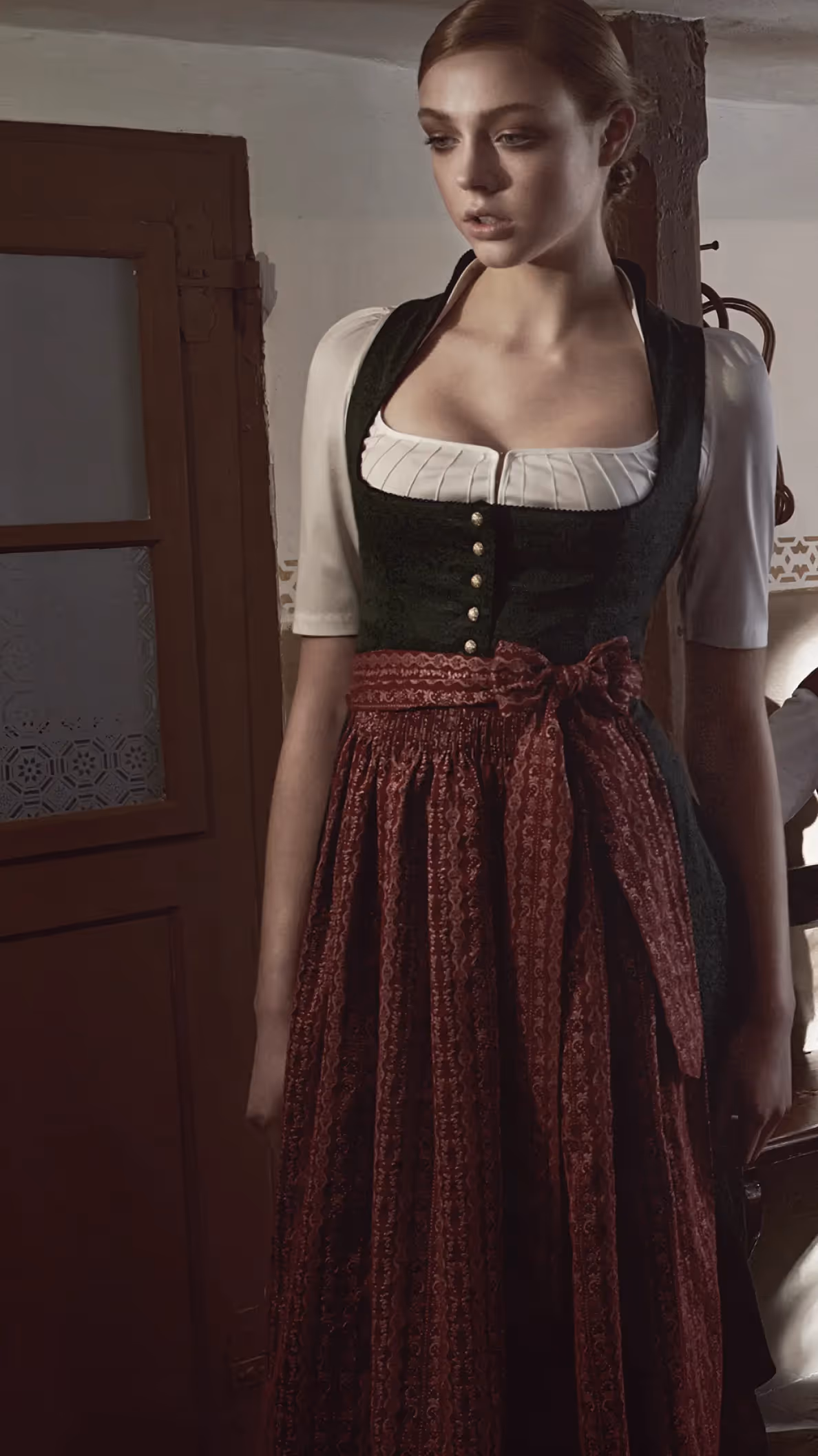 Drei Personen in Tracht sitzen an einem Holztisch in einer traditionellen Stube im warmen Licht der Gottseidank Kampagne