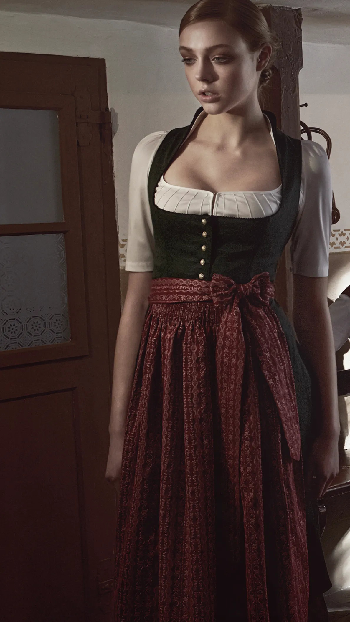 Drei Personen in Tracht sitzen an einem Holztisch in einer traditionellen Stube im warmen Licht der Gottseidank Kampagne