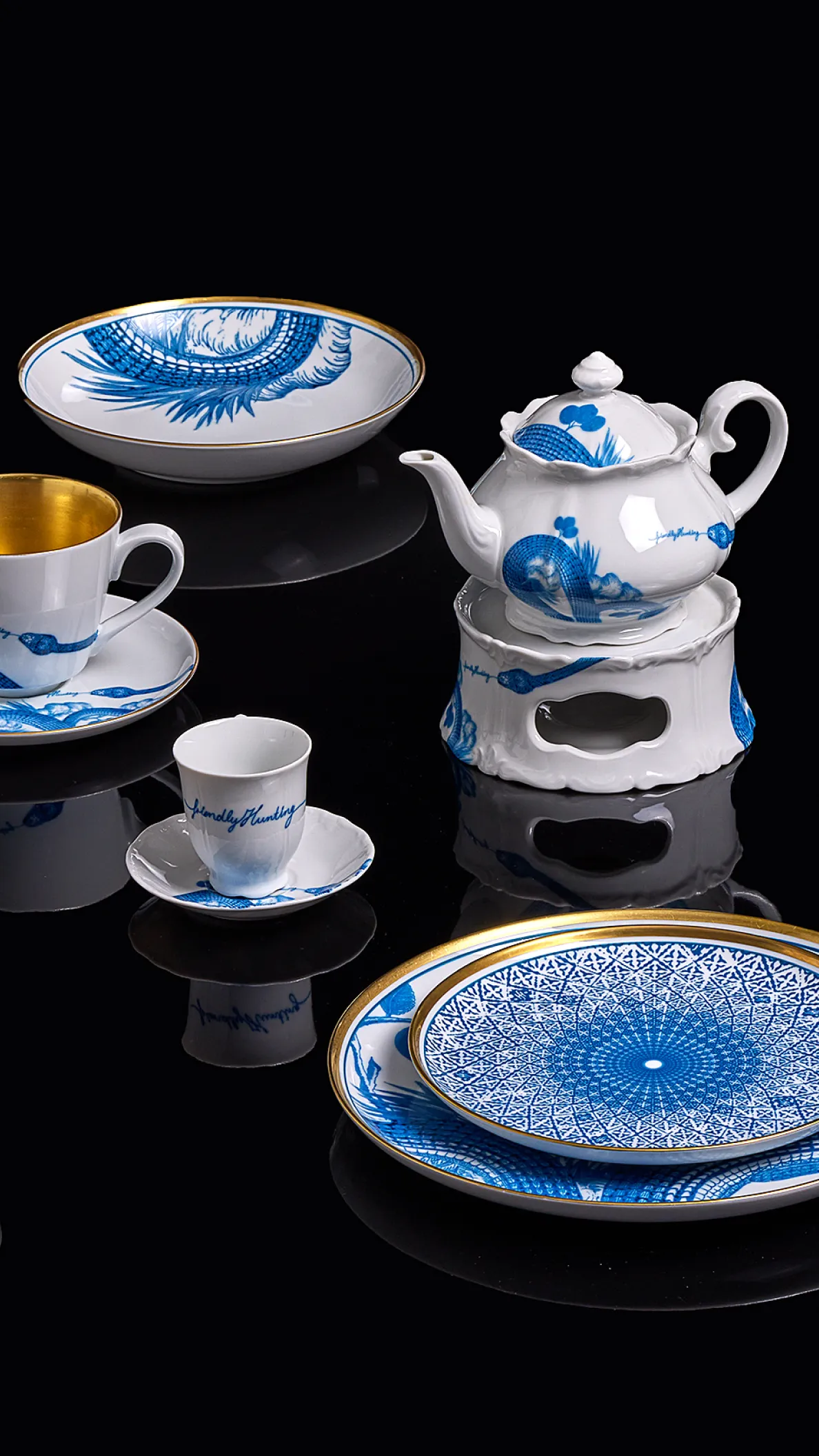 Auswahl an Porzellan und Geschirr mit blauem Muster und goldenen Details auf schwarzem Hintergrund aus der Friendly Hunting Kollektion