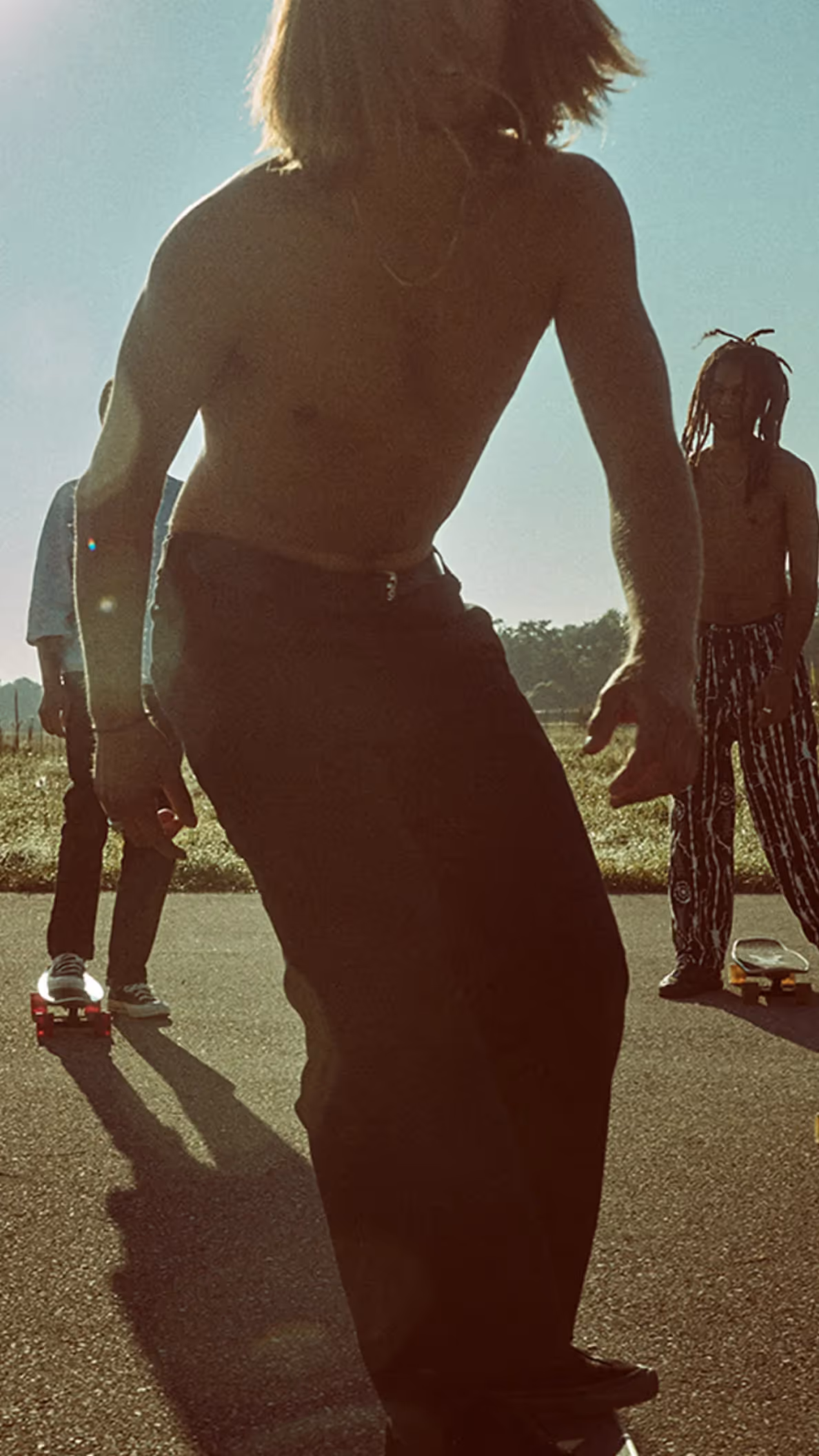 Gruppe von Jugendlichen fährt Skateboard auf einer Straße im warmen Sonnenlicht für die BANZAI Kampagne