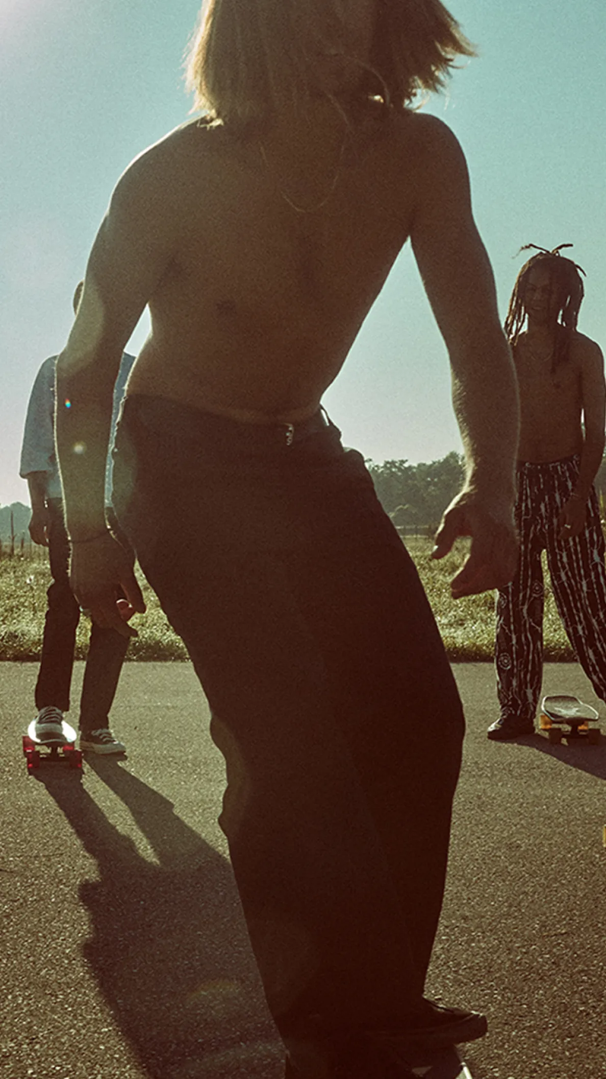 Gruppe von Jugendlichen fährt Skateboard auf einer Straße im warmen Sonnenlicht für die BANZAI Kampagne