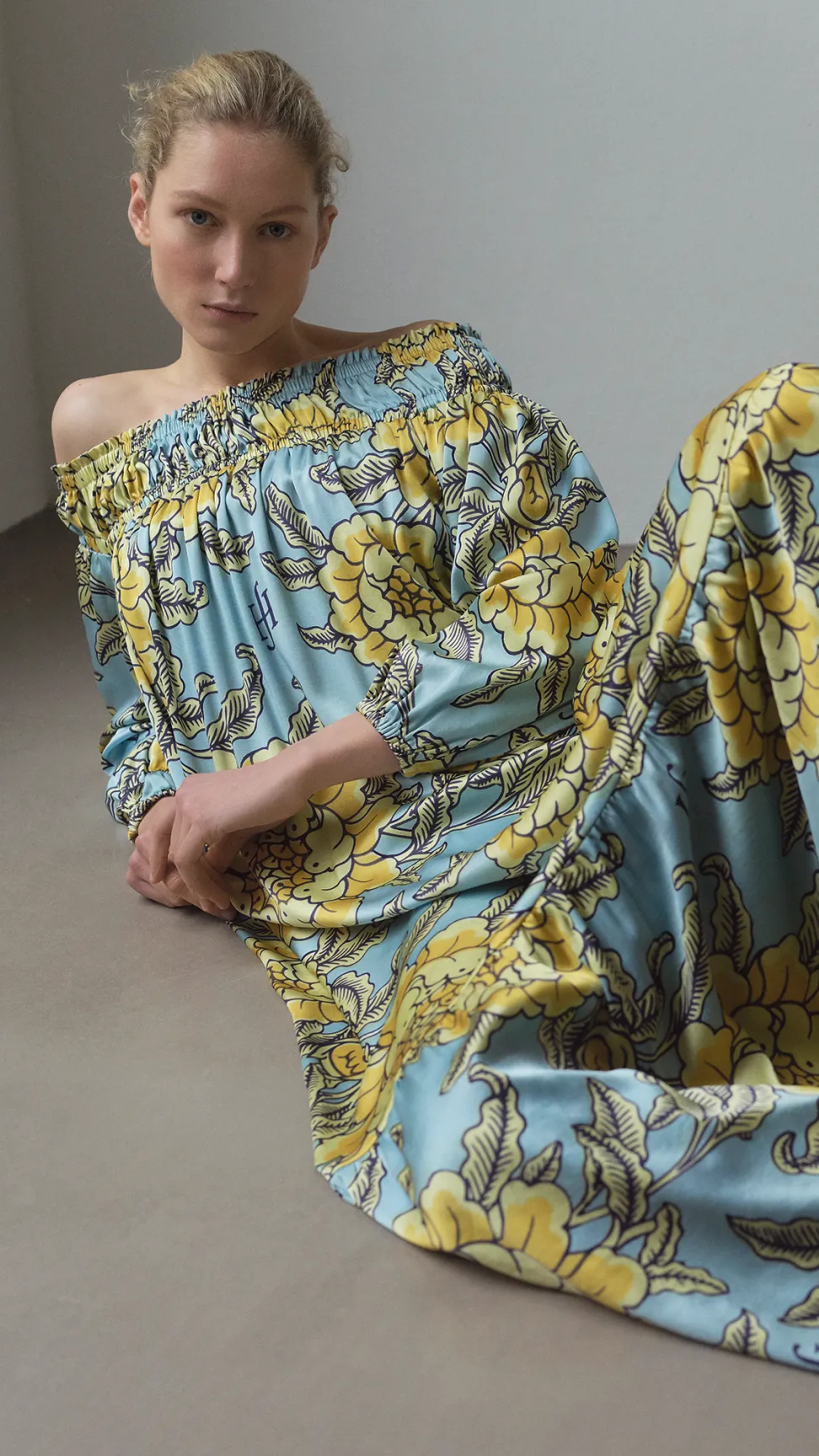 Frau liegt in einem farbenfrohen Kleid mit floralen Mustern aus der Friendly Hunting Kollektion