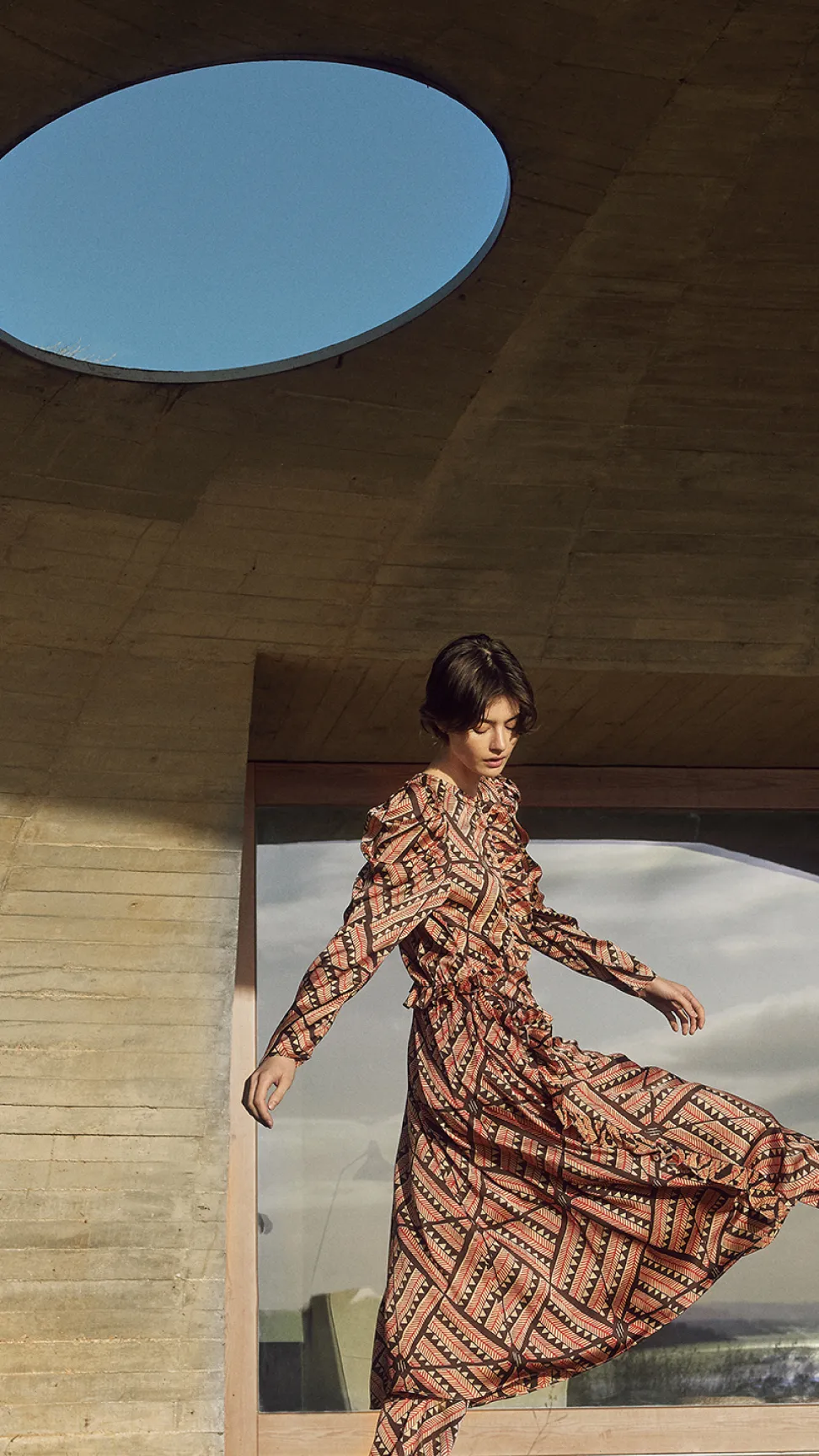 Frau in fließendem Kleid bewegt sich durch architektonische Kulisse im poetischen Stil der Friendly Hunting Kampagne