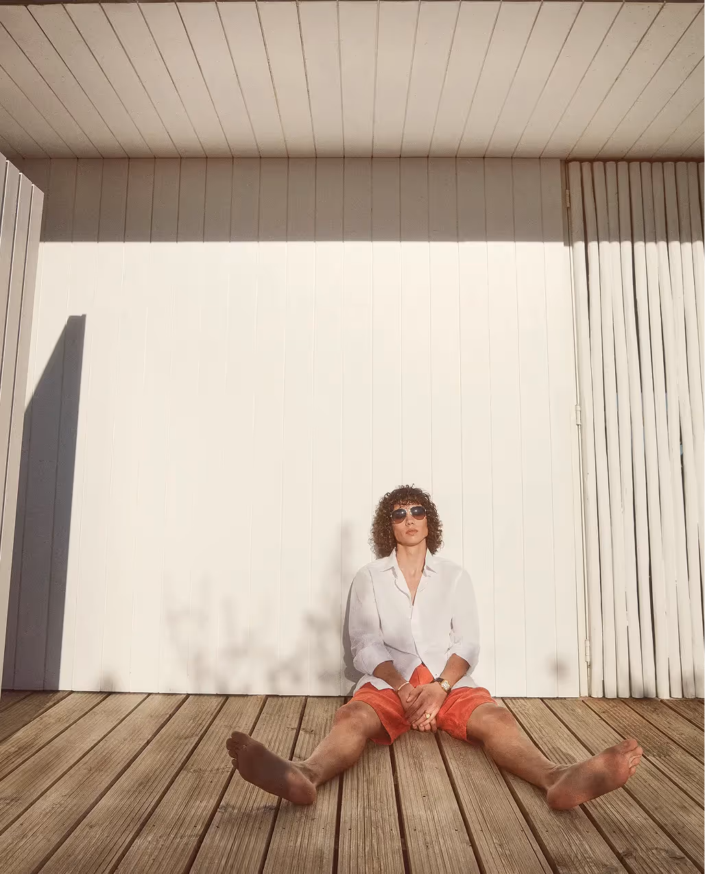 Mann sitzt vor minimalistischer Architektur im ruhigen Sommerlook der 04651 Kollektion