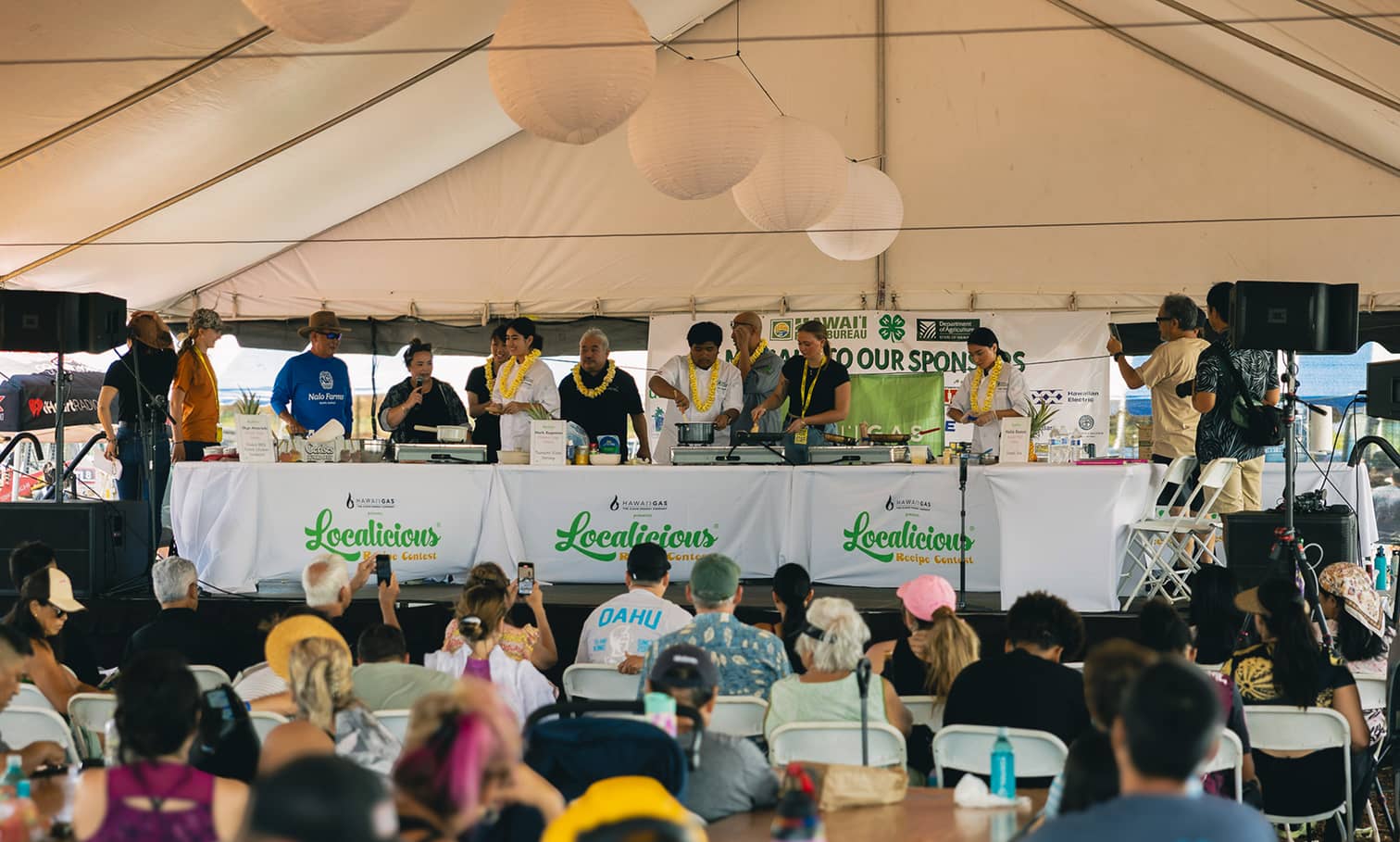High school students standing on stage behind a white table presented with awards for the Localicious Recipe Contest.