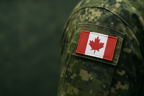 Canadian flag patch on the sleeve of a green camouflage military uniform.