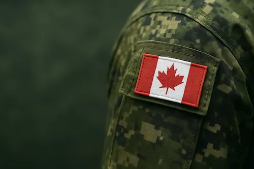 Canadian flag patch on the sleeve of a green camouflage military uniform.