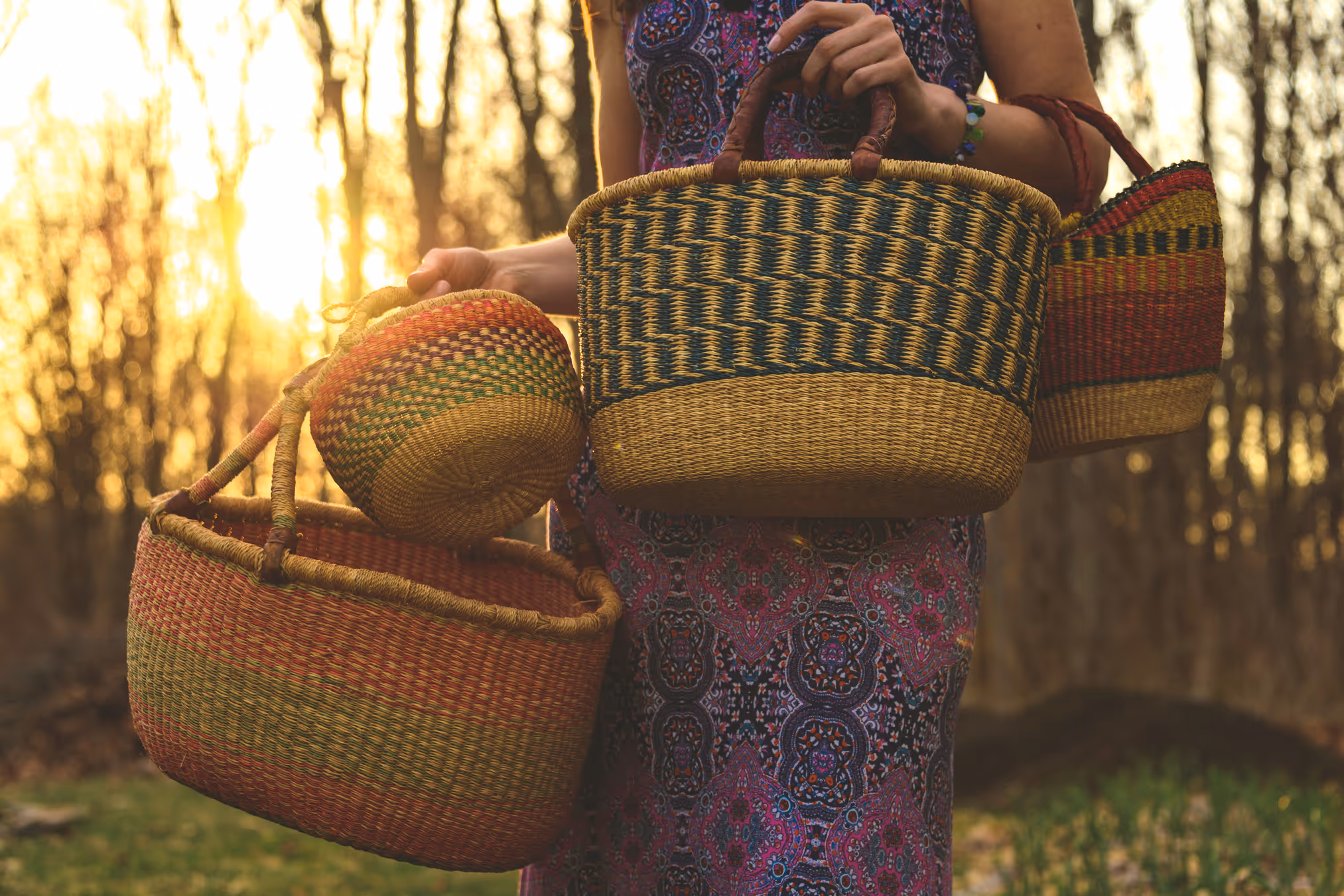 Susan Cote holding woven baskets outdoors, representing gathering and connection to nature