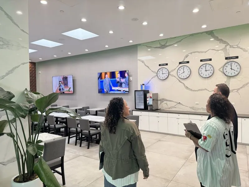Visitors tour a modern school space with world clocks on the wall