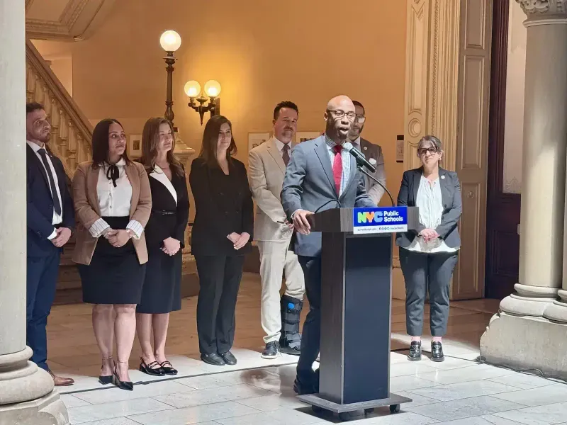 A speaker addresses guests at an NYC Public Schools podium as the ACE team looks on