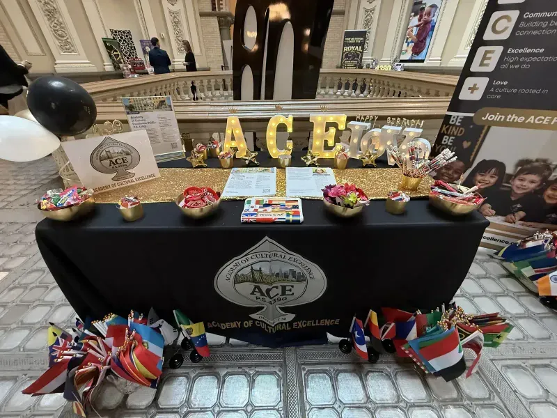 ACE welcome table with gold ACE letters, balloons and flags from around the world