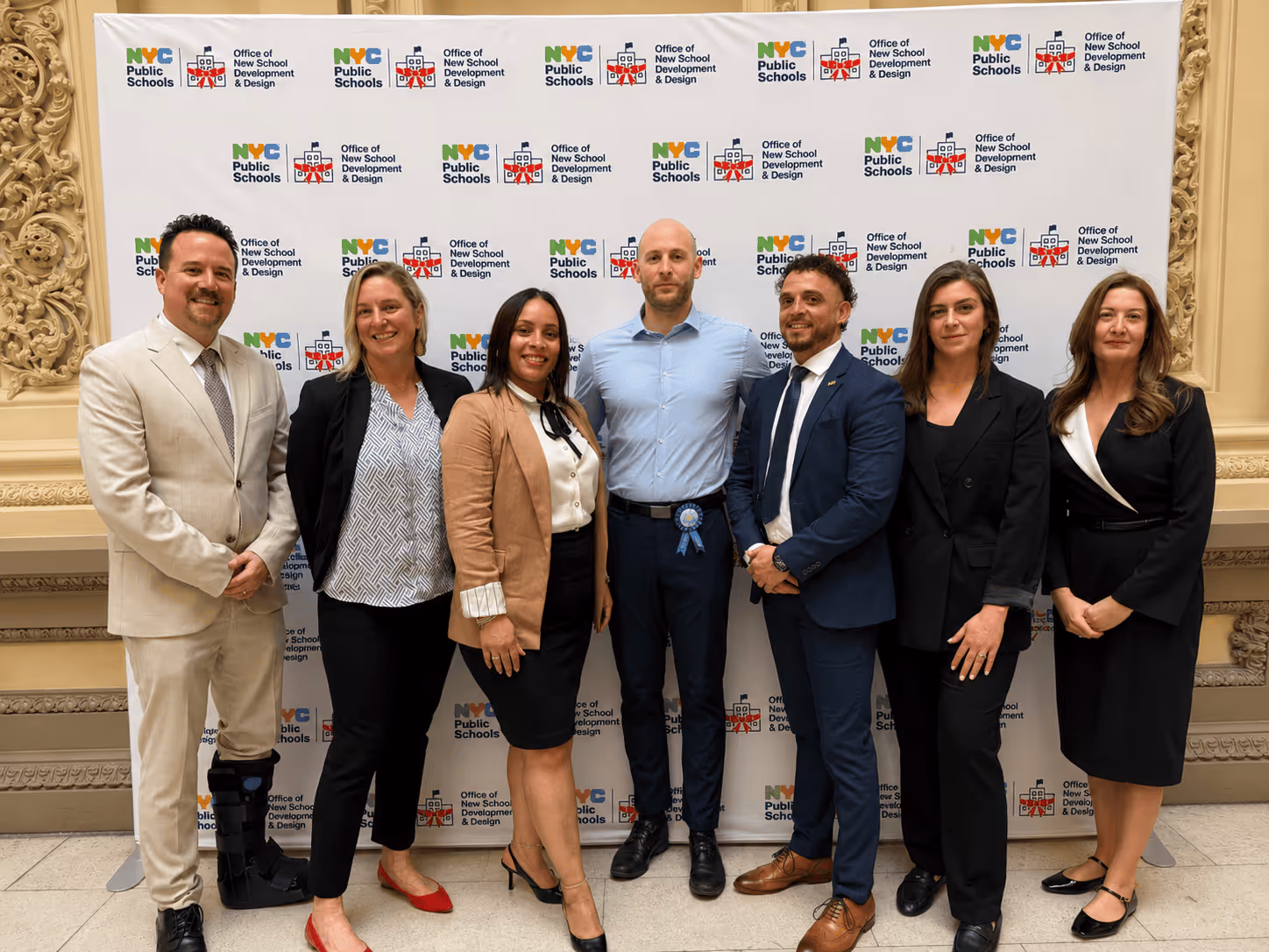 Seven members of the ACE founding team pose at the NYC Public Schools backdrop