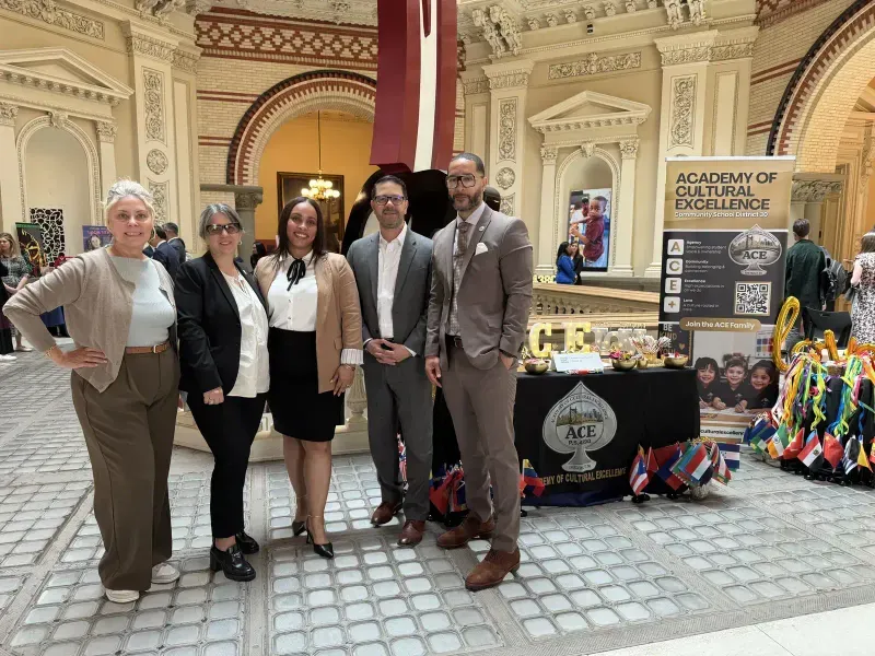 ACE staff and guests pose together in front of the ACE display table