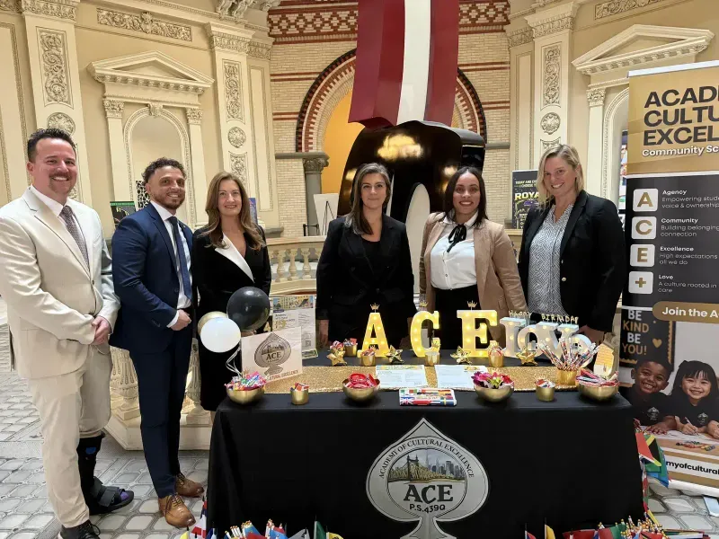 ACE team members gather behind the Academy of Cultural Excellence welcome table