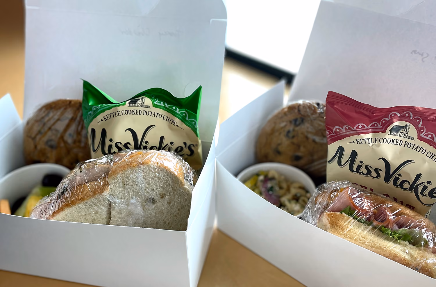 Two Squatters boxed lunches with wrapped sandwiches, kettle chips, cookies and a side salad