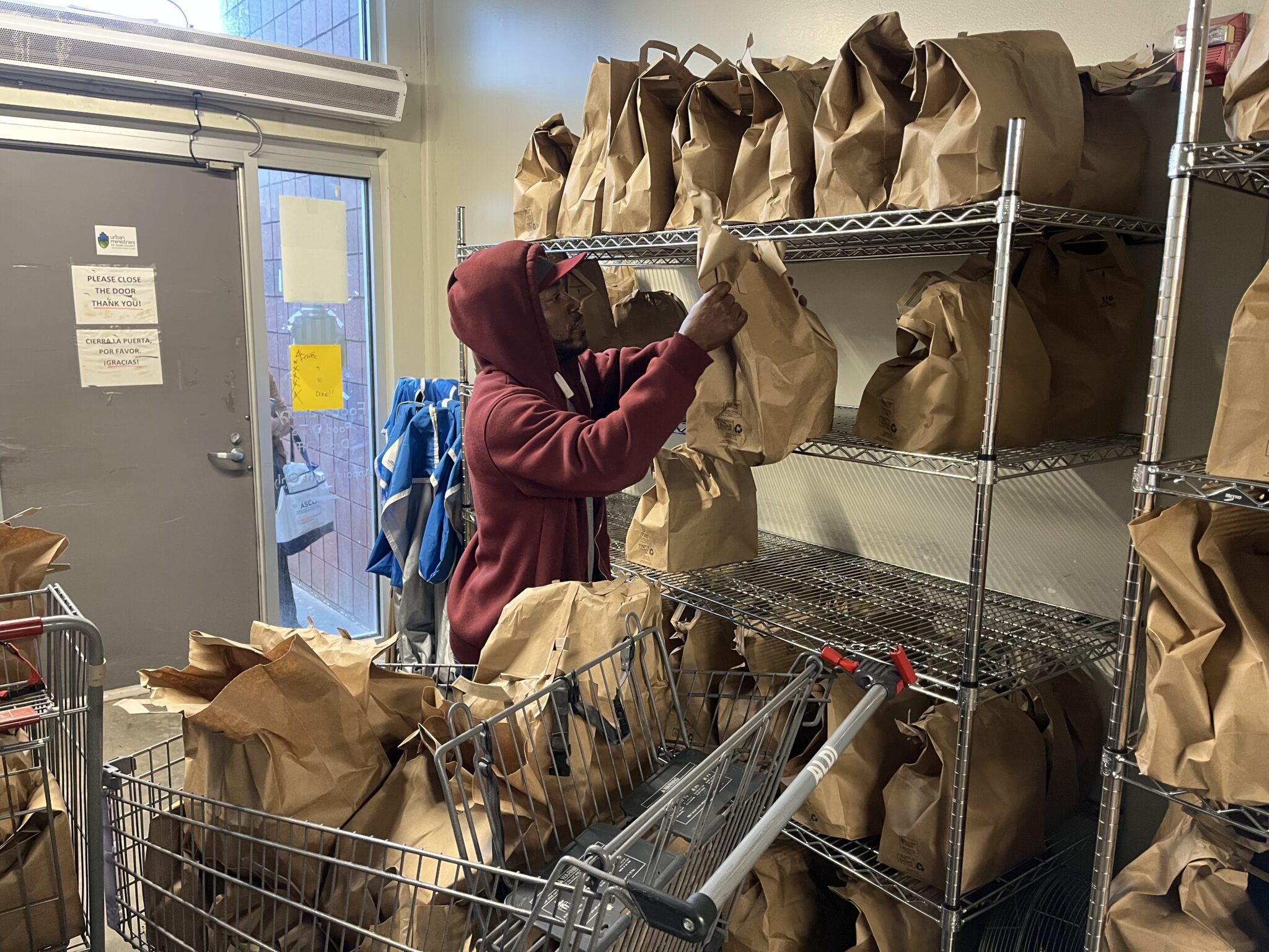food pantry manager Jerry Leslie loading groceries into a cart.