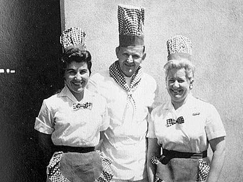 An image of 3 people, a man and two women. They are wearing  Hof's Hut uniforms with bow ties scarfs and hats