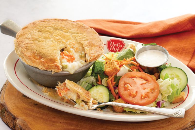 HOF'S HUT PLATE WITH STEAK, EGGS AND HASHBROWNS. THERE IS ALSO A BLUEBERRY MUFFIN IN A SMALL HOF'S HUT SAUCER, BEHIND THE LARGE BREAKFAST PLATE.