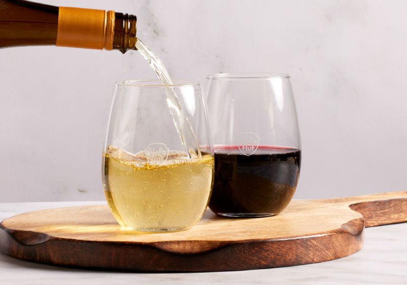 A SHORT WINE GLASS WITH RED WINE AND A SHORT WINE GLASS WITH WHITE WINE BEING POURED IN. 