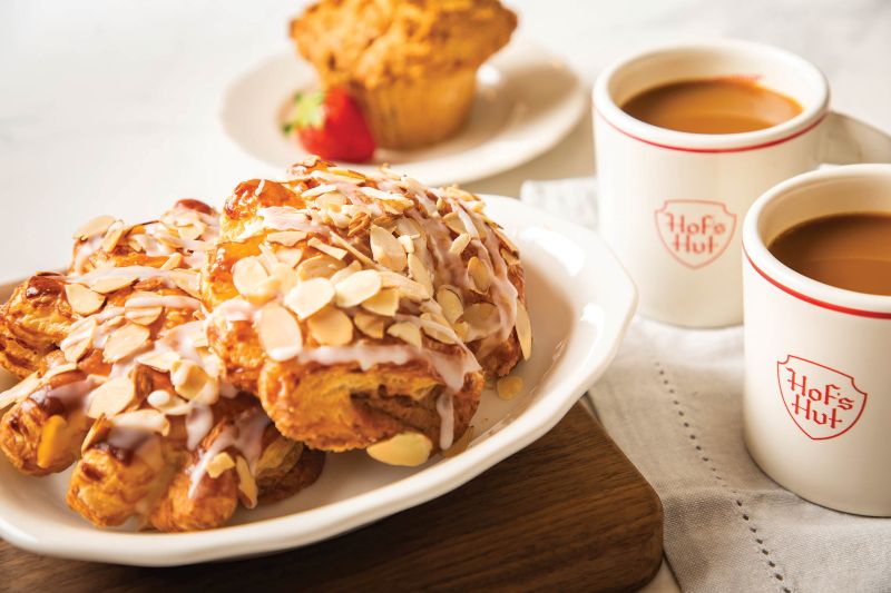 A LARGE BEAR CLAW WITH ALMONDS AND A CUP OF COFFEE ON THE SIDE.