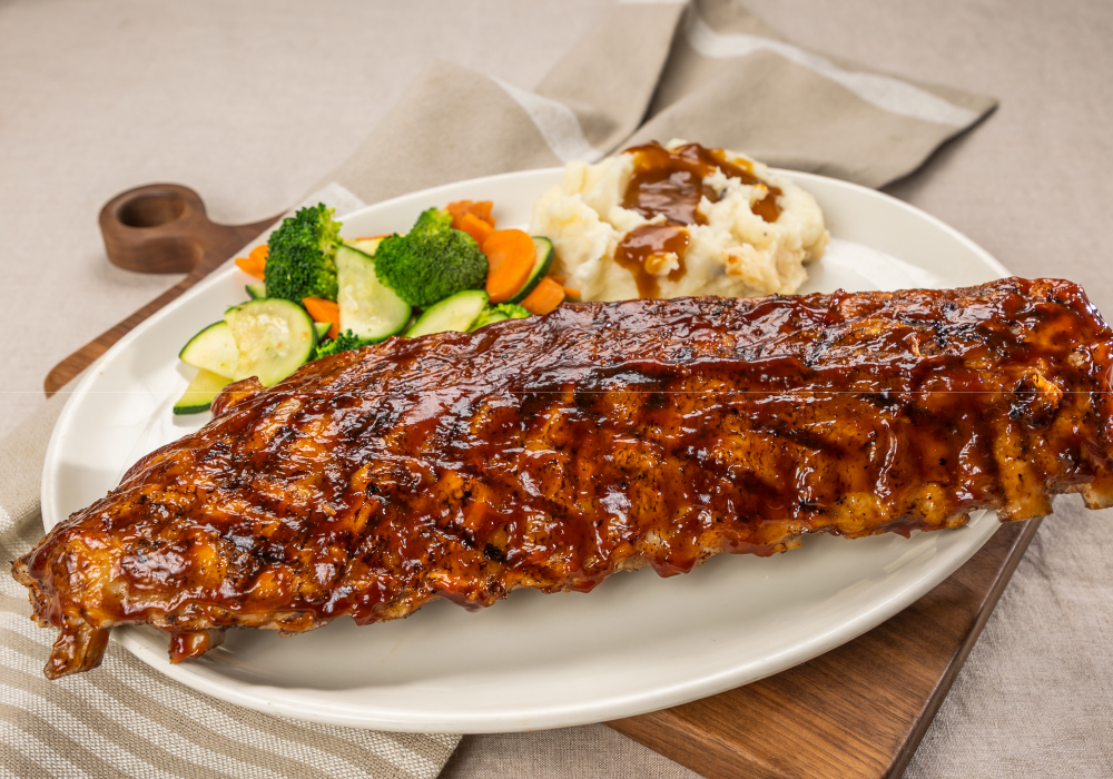 A large plate with meatloaf mashed potatoes and vegetables.  The meatloaf and mashed potatoes are smothered in brown gravy. 