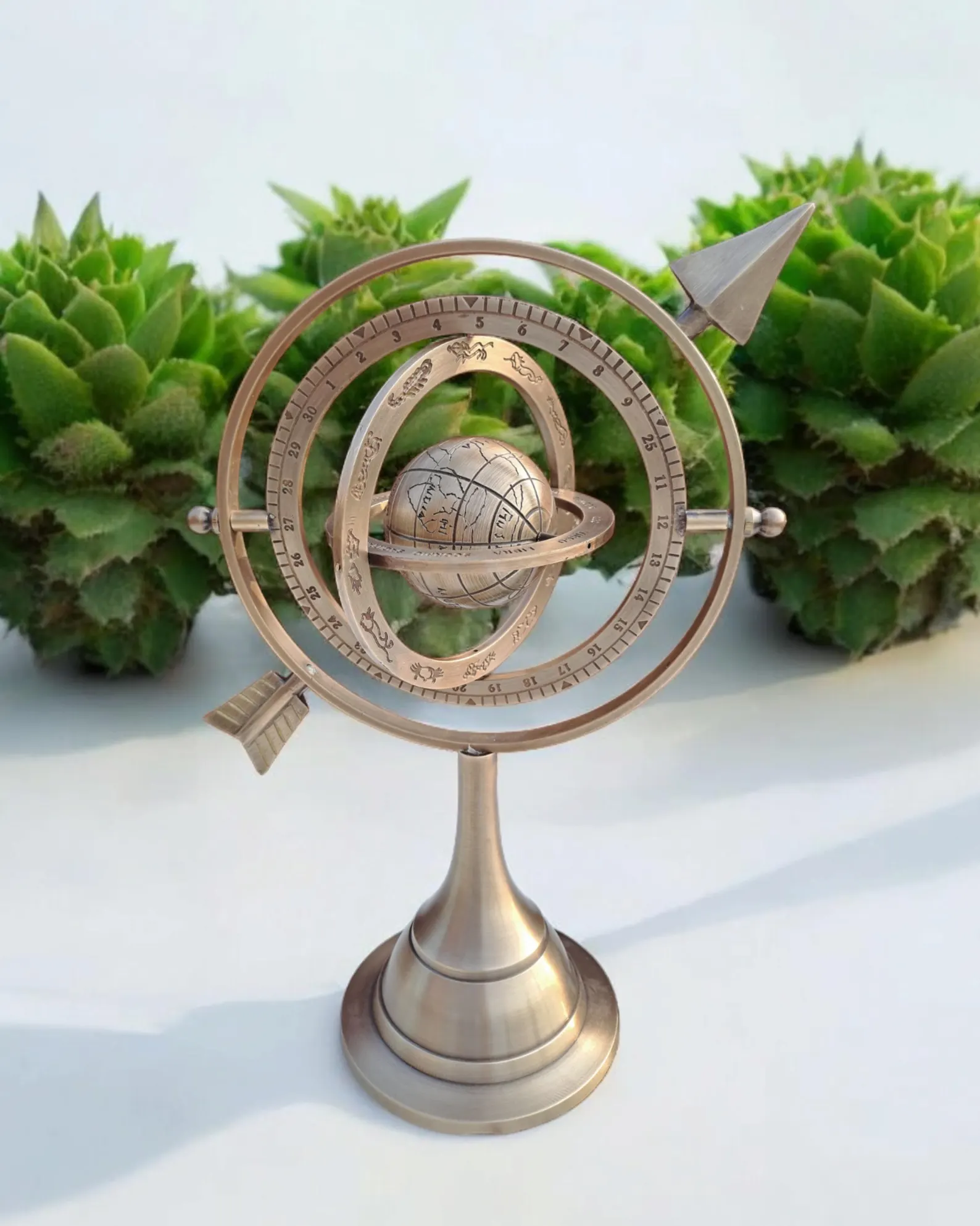 Decorative brass armillary sphere with arrow pointers and engraved celestial rings