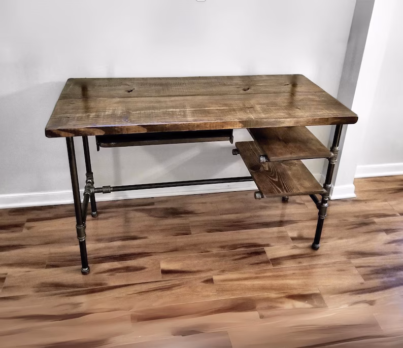 Industrial steampunk writing desk with dark wood top and metal pipe frame