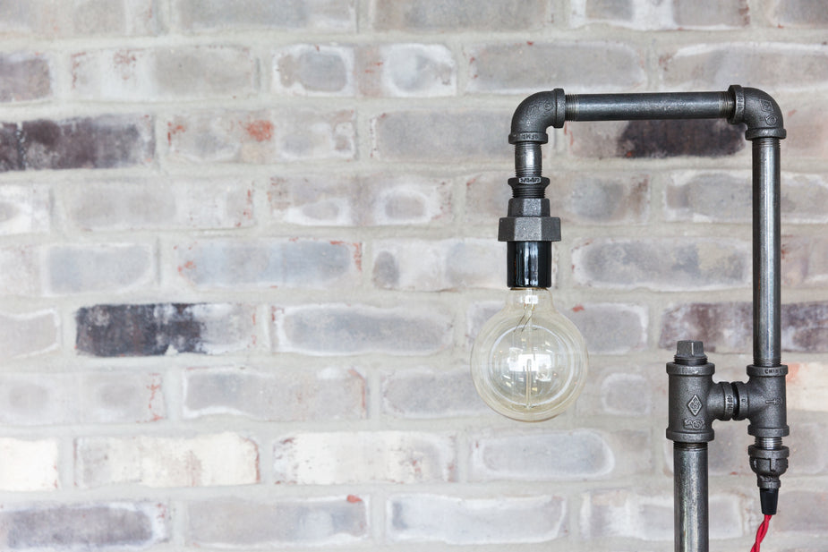 Iron piping against a white brick wall.