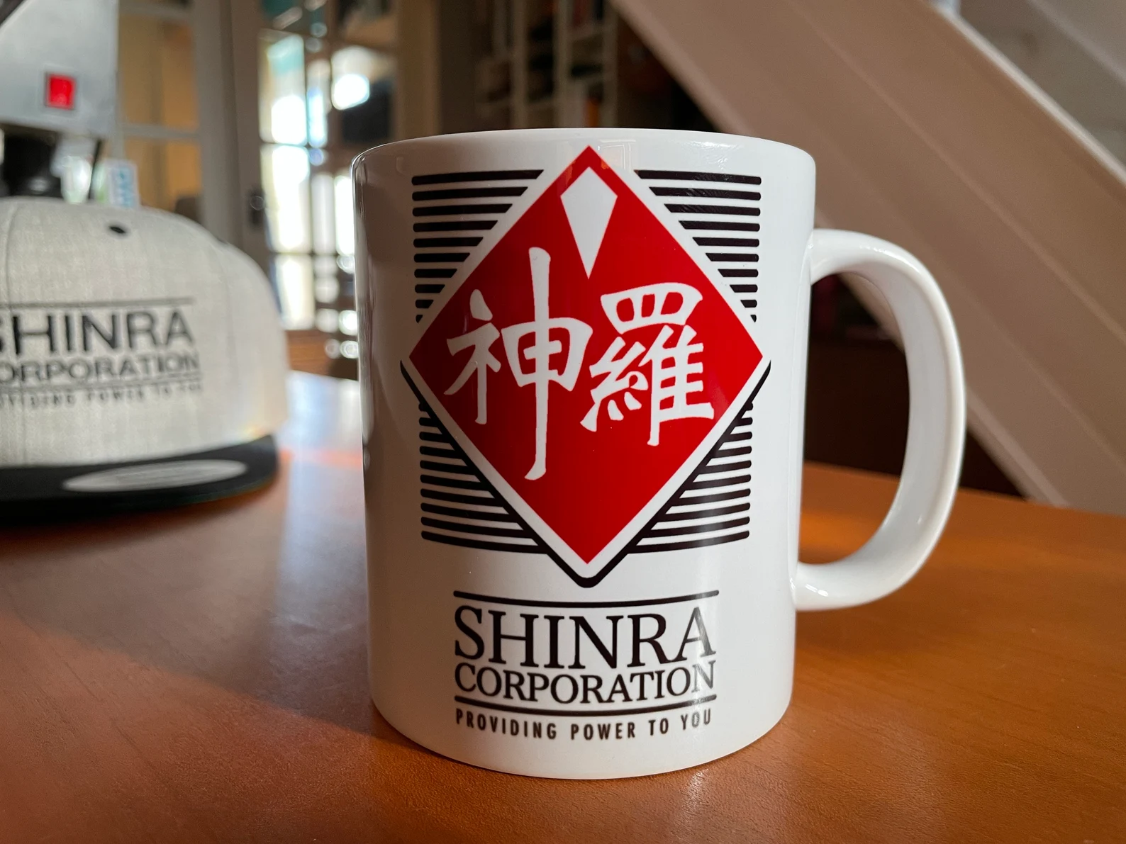 White Shinra Corporation coffee mug with red logo on a wooden desk