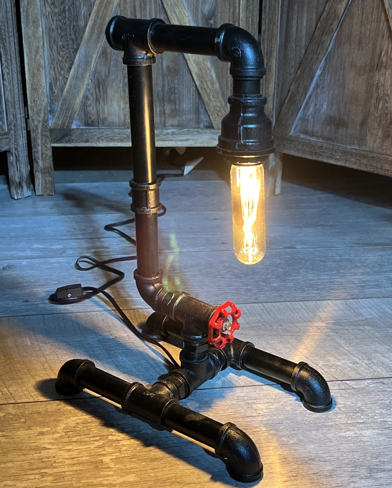 Industrial black pipe table lamp with exposed Edison bulb and red valve handle detail