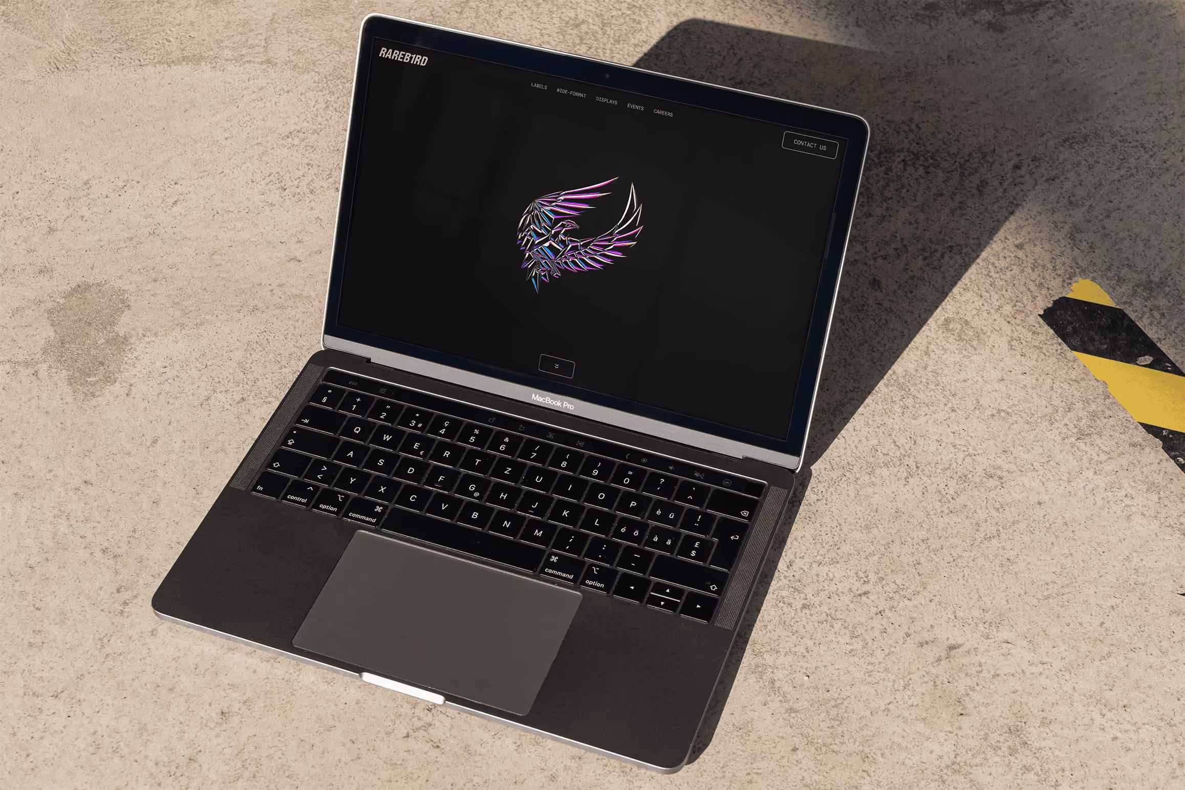 Rareb1rd website home screen with 3D logo on laptop with concrete floor