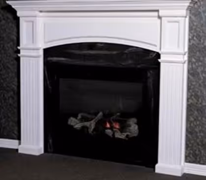 Black fireplace with white decorative mantel and a few glowing embers inside.