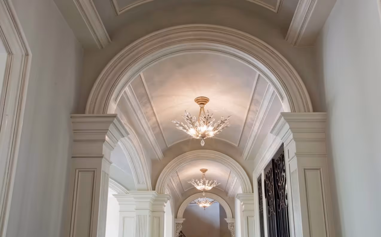 Decorative hallway with a series of elegant arches and ornate chandeliers hanging from a paneled ceiling.