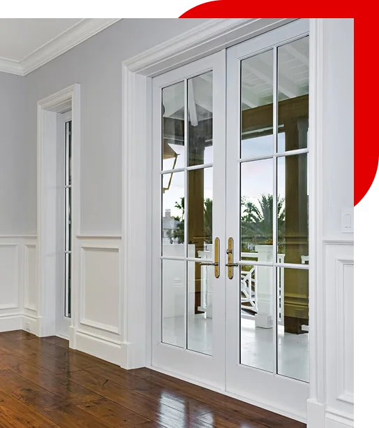 White French doors with glass panels and brass handles opening to a porch with wooden beams and palm trees visible outside.
