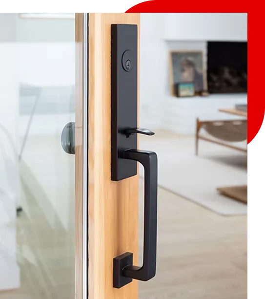 Close-up of a modern black door handle and lock on a wooden framed glass door with a blurred living room in the background.