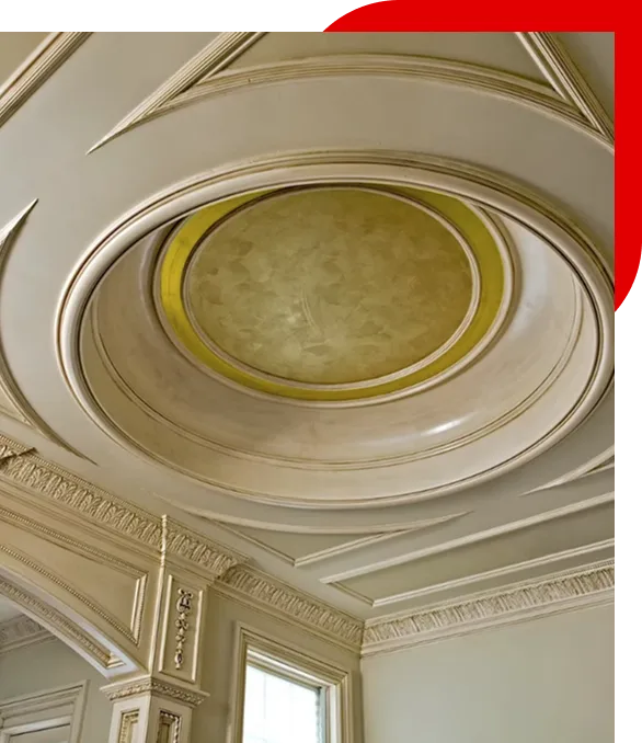 Ornate ceiling medallion with layered circular design and gold center in a room with decorative crown molding and a window.