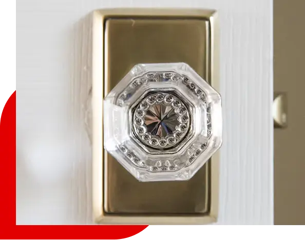 Close-up of a vintage clear glass octagonal door knob with a brass rectangular backplate on a white door.