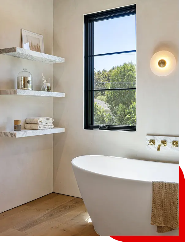 Modern bathroom with a white freestanding bathtub, black-framed window showing green trees in Arcadia, CA.