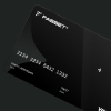 Black credit card angled on a dark surface showing the chip and partially visible numbers.