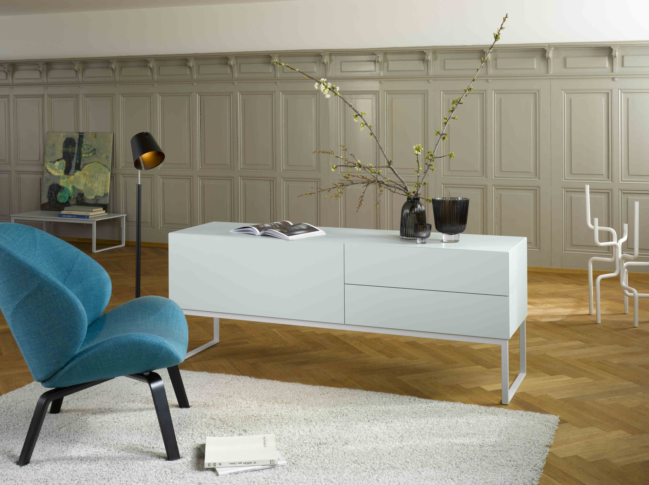 Türkisfarbener Relaxsessel neben weissem Möbel