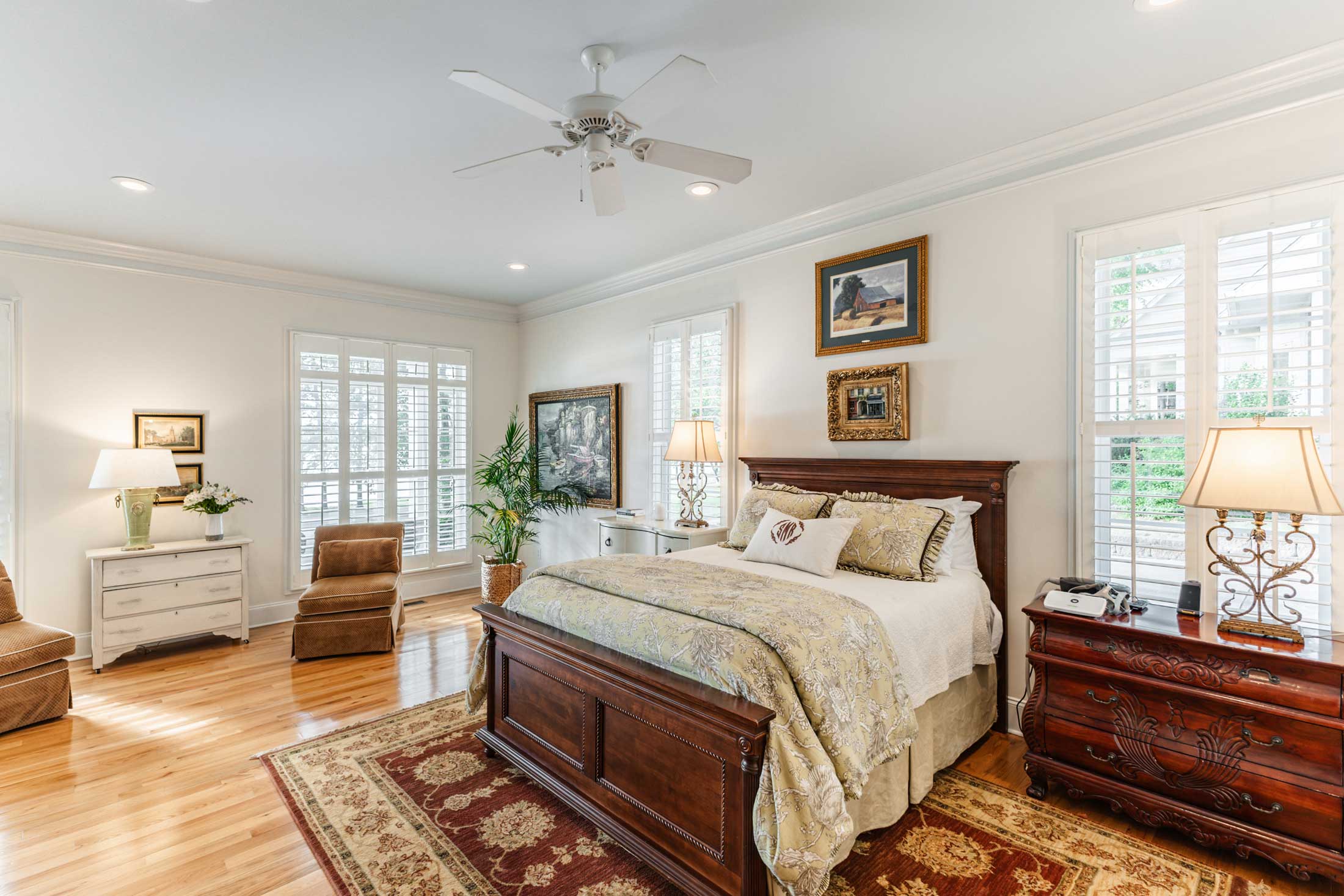 Modern kitchen with marble island, white cabinets, stainless steel appliances, and large windows overlooking trees.