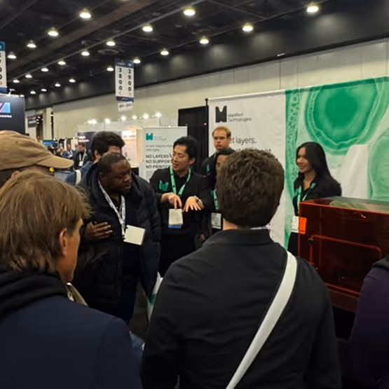 A group of people standing around a booth talking.