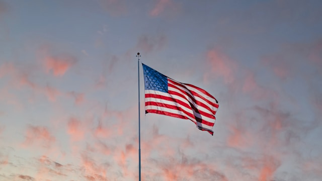 An american flag with sunset sky behind