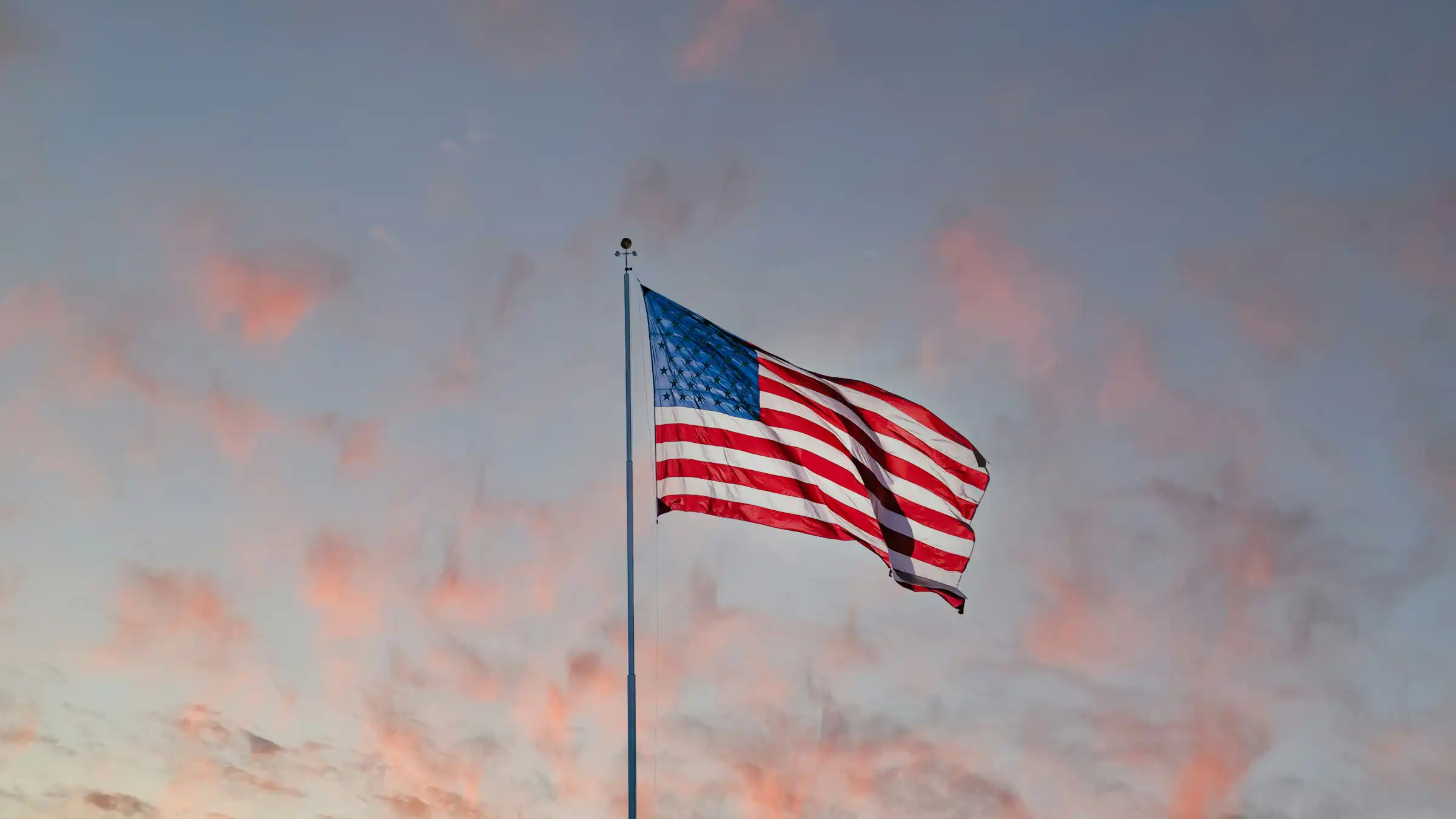 An american flag with a sunset sky in the background
