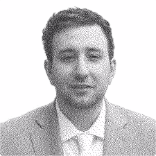 Headshot of a man with short dark hair wearing a light-colored suit jacket and white shirt against a white background.