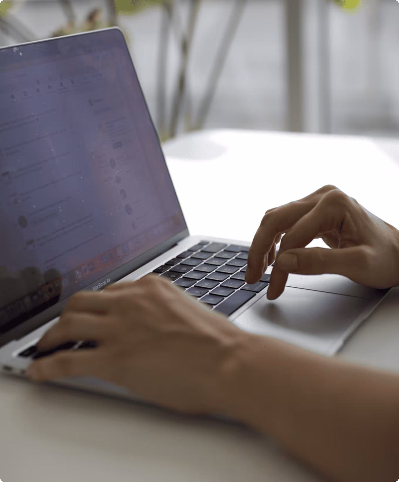 Person typing on a MacBook Air laptop with a blurred background.
