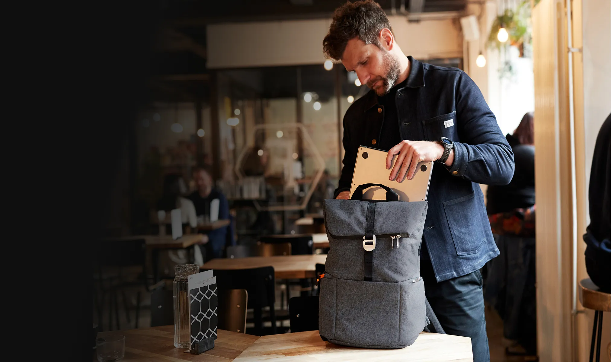 A man packs a Shutter backpack in an office setting.